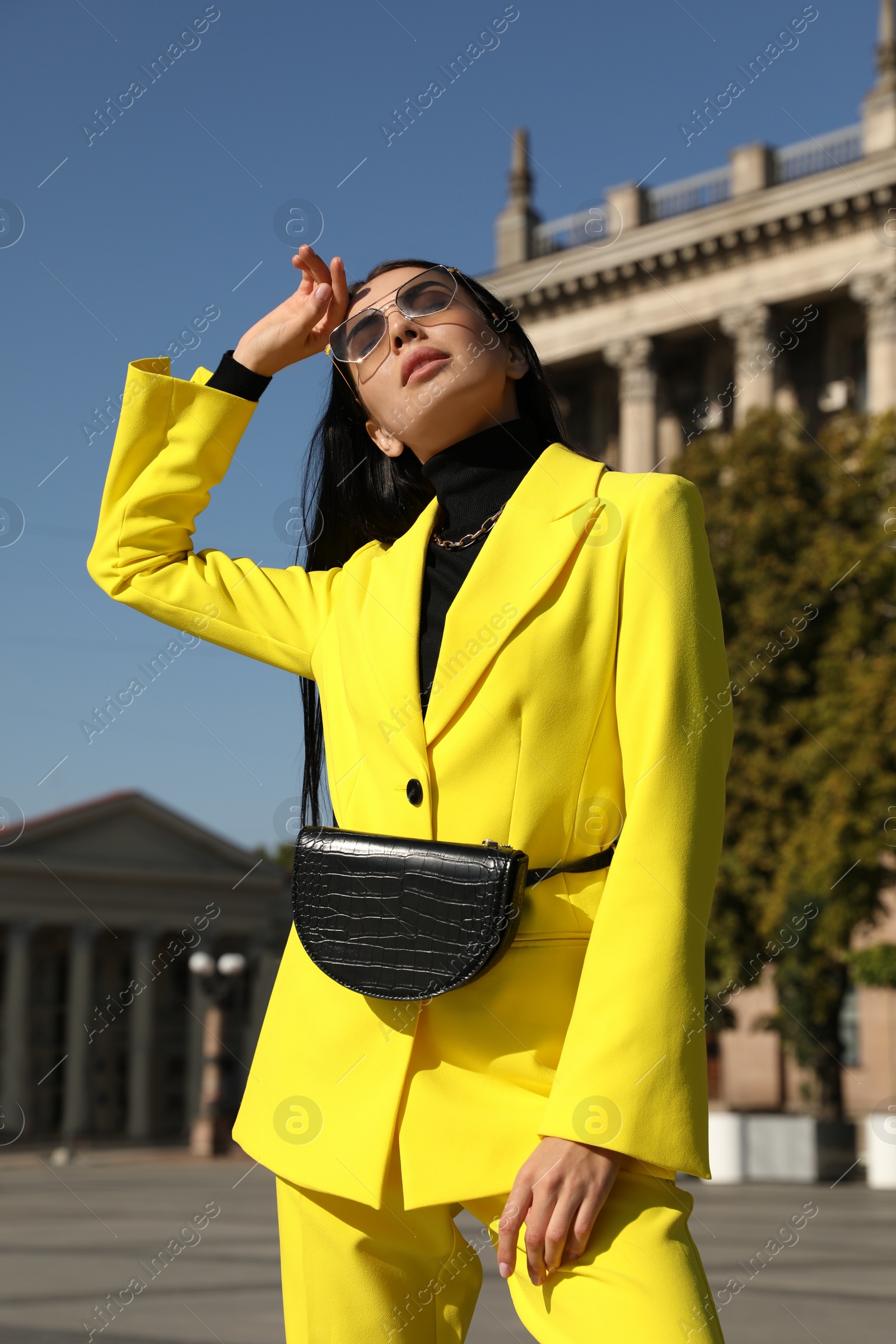 Photo of Beautiful young woman with stylish waist bag on city street