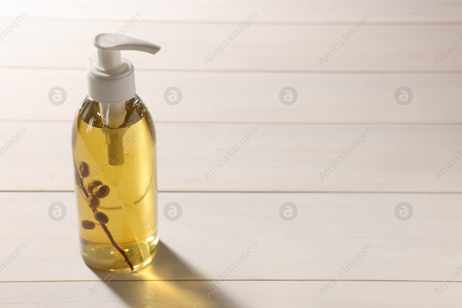 Photo of Dispenser of liquid soap on white wooden table, space for text