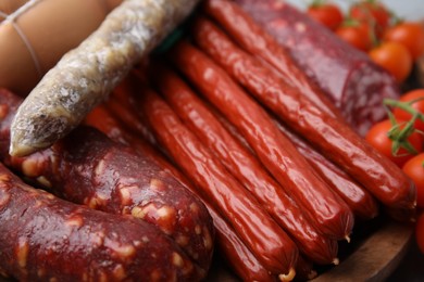 Photo of Different types of tasty sausages and tomatoes on table, closeup