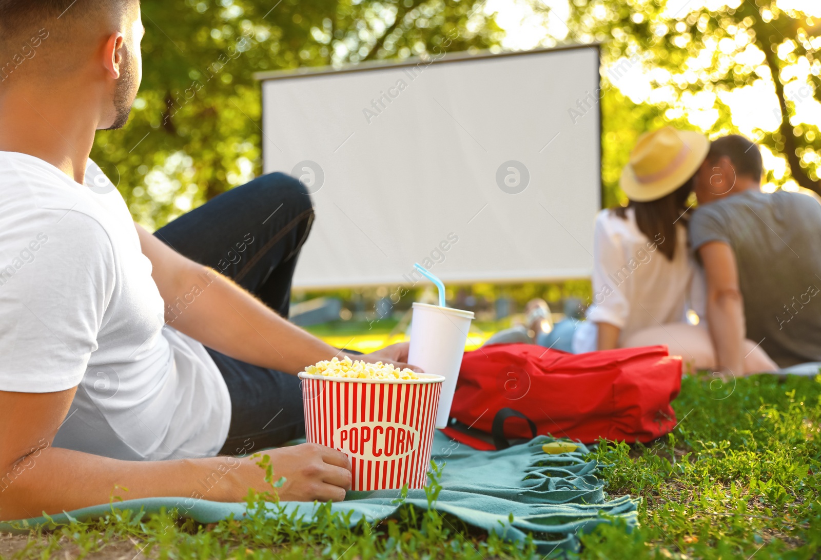 Photo of Young man with popcorn watching movie in open air cinema, closeup. Space for text