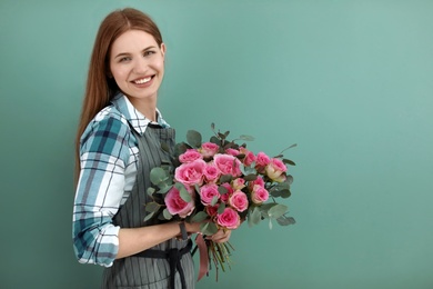 Female florist holding bouquet of beautiful flowers on color background