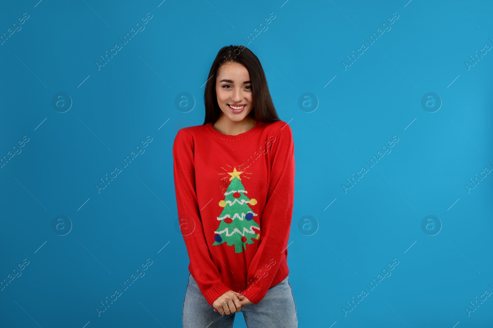 Photo of Young woman in Christmas sweater on blue background