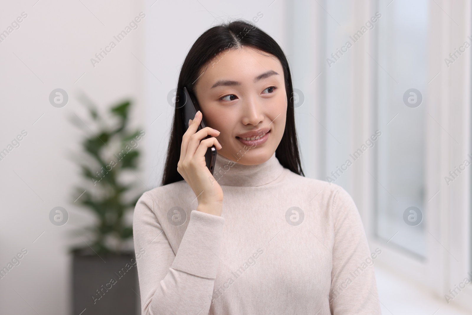 Photo of Portrait of smiling businesswoman talking on smartphone in office