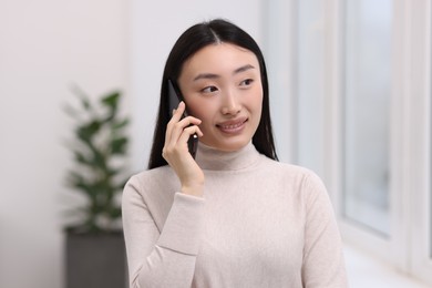 Photo of Portrait of smiling businesswoman talking on smartphone in office