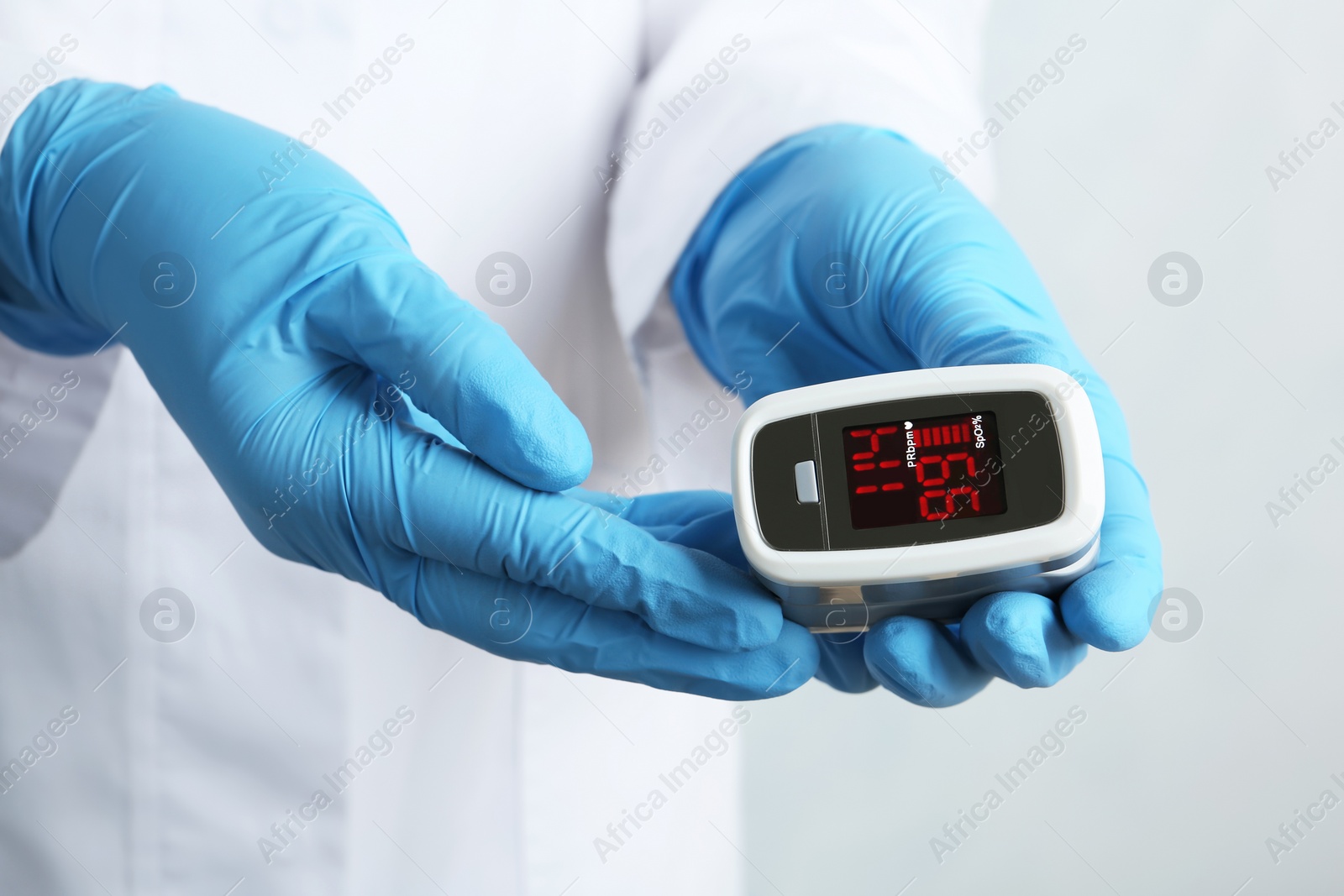 Photo of Doctor holding modern fingertip pulse oximeter, closeup