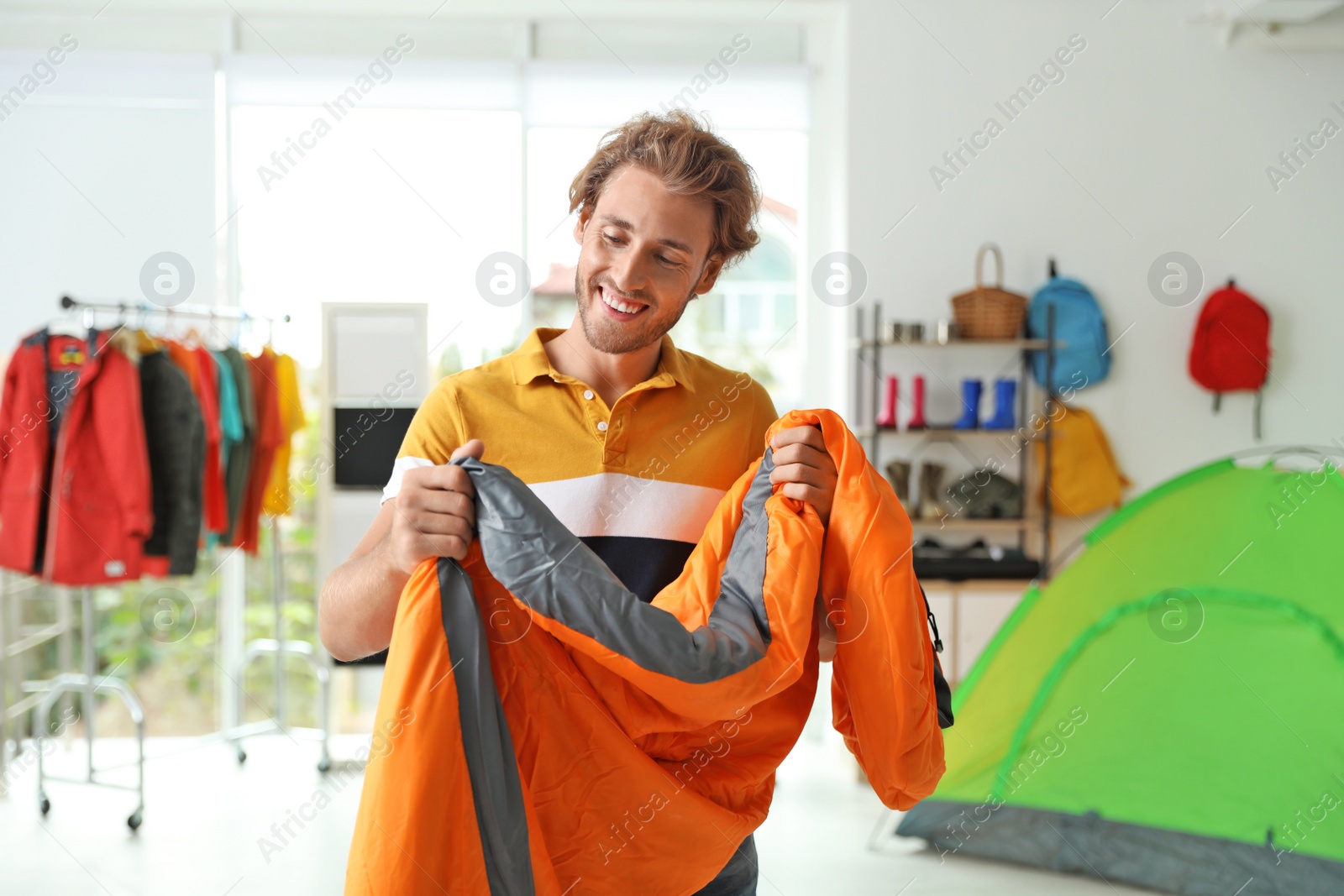 Photo of Young man choosing sleeping bag in store