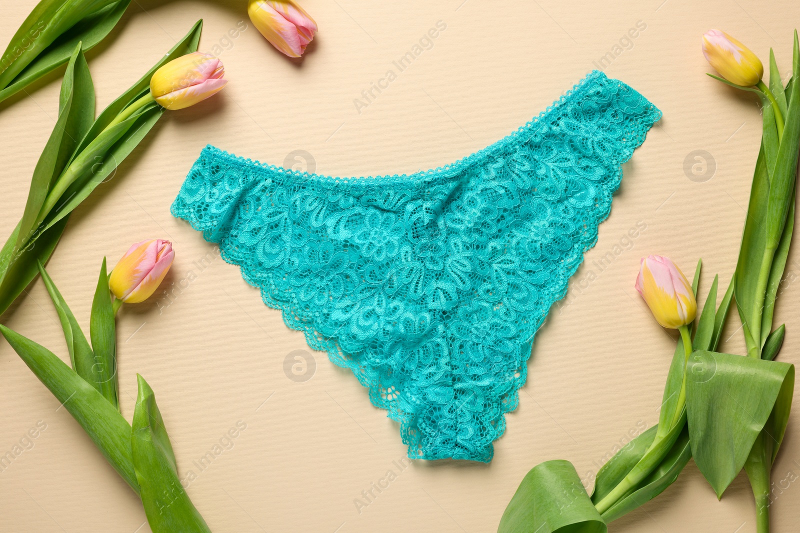 Photo of Elegant light blue women's underwear and beautiful tulips on beige background, flat lay