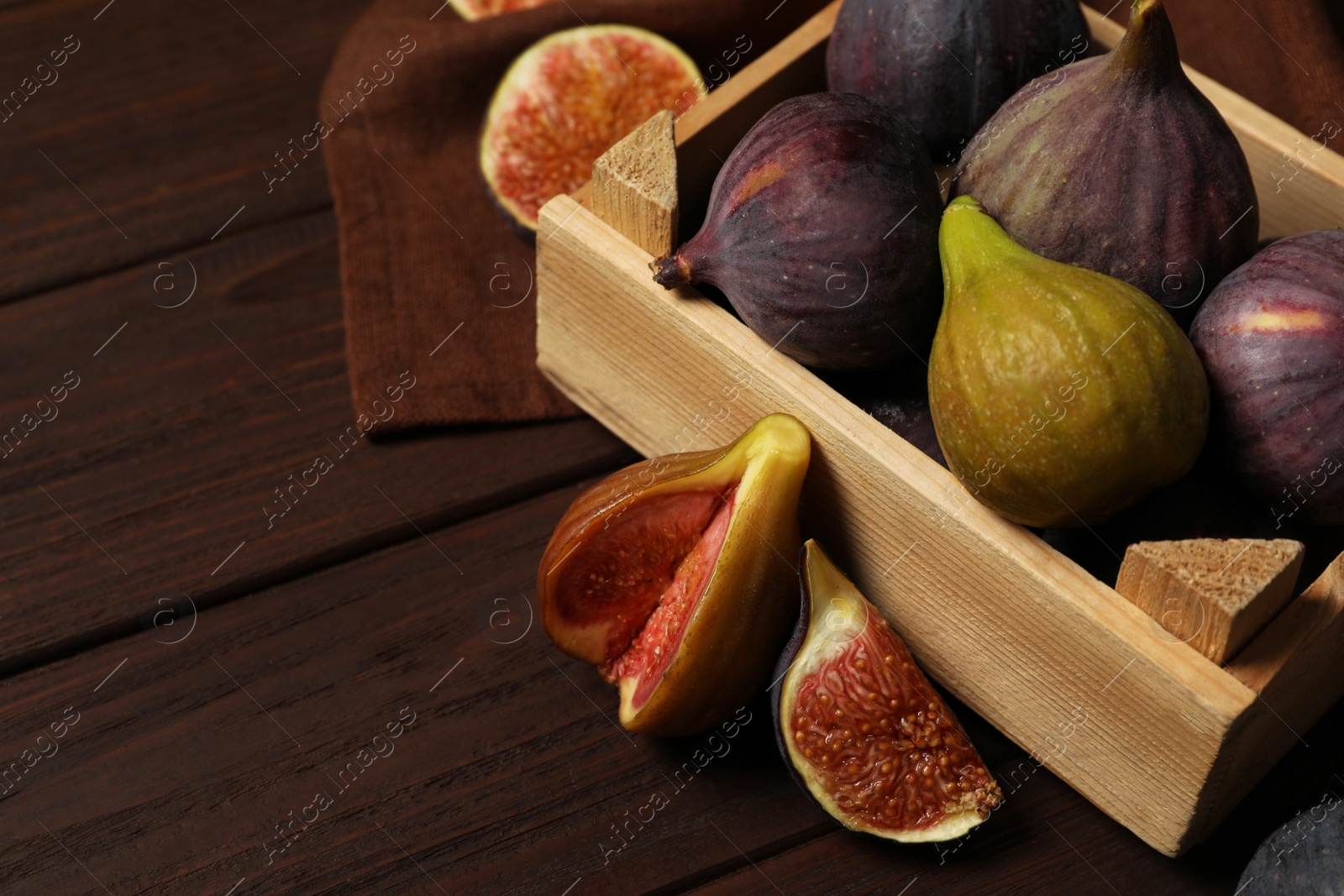 Photo of Tasty raw figs in crate on wooden table, closeup