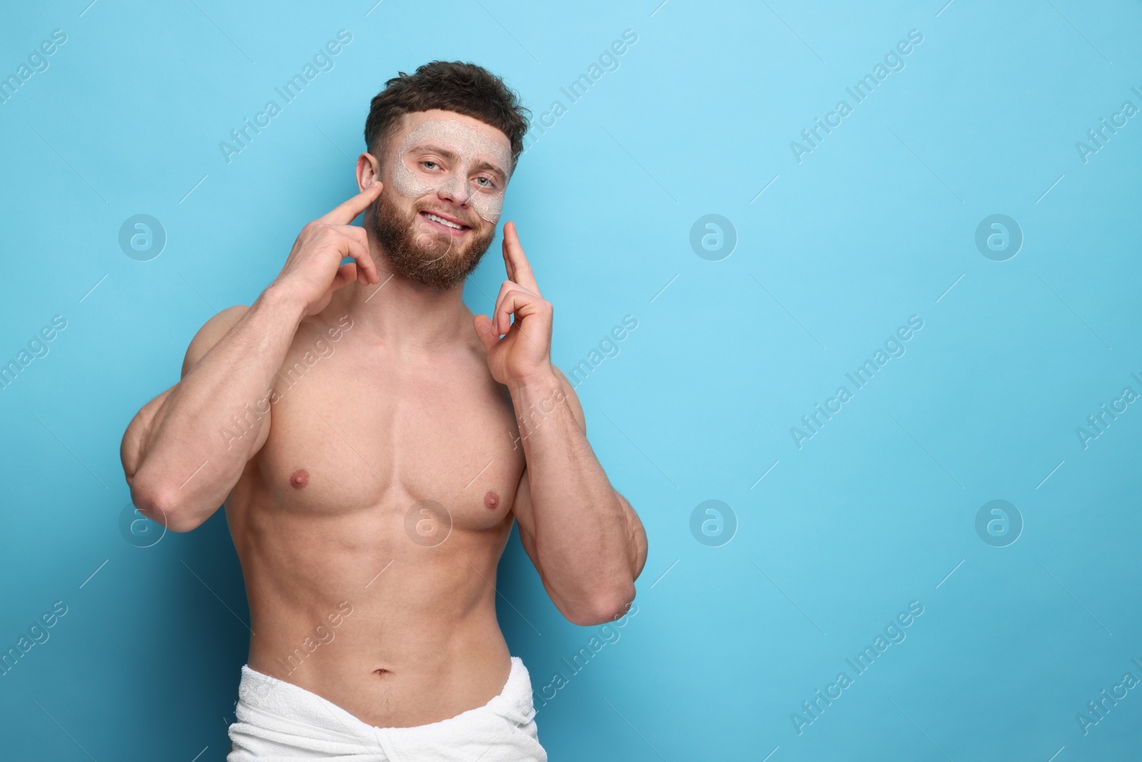 Photo of Handsome man with facial mask on his face against light blue background, space for text