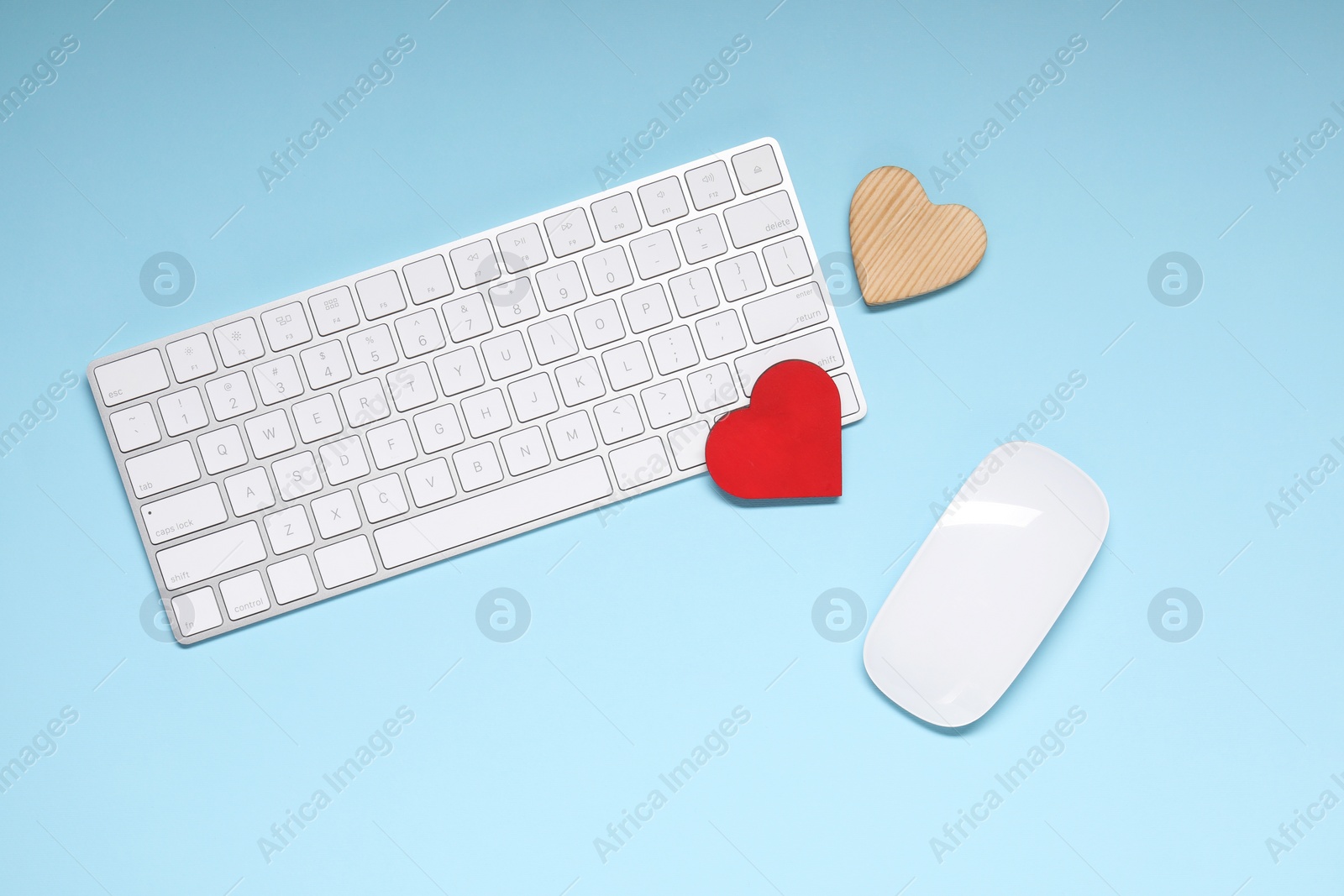 Photo of Long-distance relationship concept. Keyboard, computer mouse and decorative hearts on light blue background, flat lay