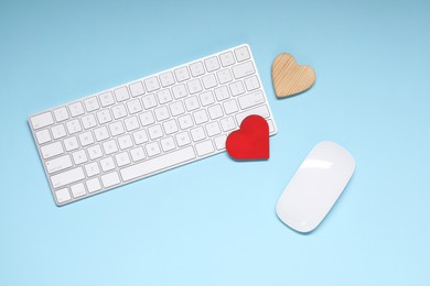 Photo of Long-distance relationship concept. Keyboard, computer mouse and decorative hearts on light blue background, flat lay