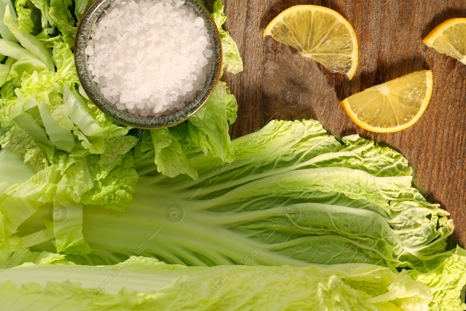 Photo of Fresh Chinese cabbage, salt and lemon on wooden table, flat lay