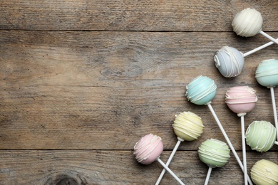 Photo of Sweet cake pops on wooden background, flat lay. Space for text