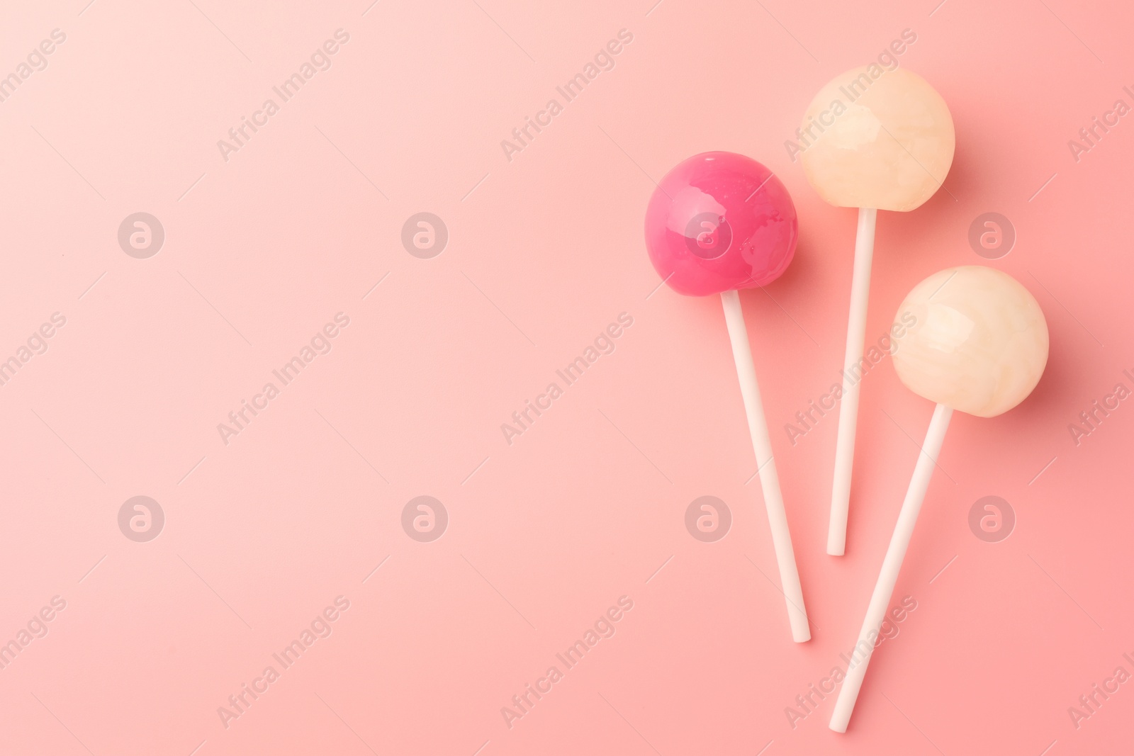 Photo of Tasty lollipops on pink background, flat lay. Space for text