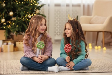 Photo of Cute little girls with lollipops at home. Christmas atmosphere