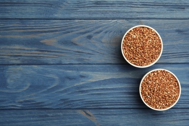 Photo of Buckwheat grains on blue wooden table, flat lay. Space for text