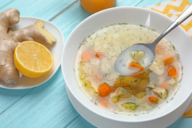 Photo of Spoon with fresh homemade soup to cure flu over bowl on wooden table