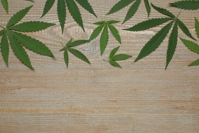Photo of Fresh green hemp leaves on wooden table, flat lay. Space for text