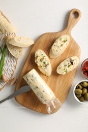 Photo of Tasty butter with green onion, olives, garlic and bread on white wooden table, top view