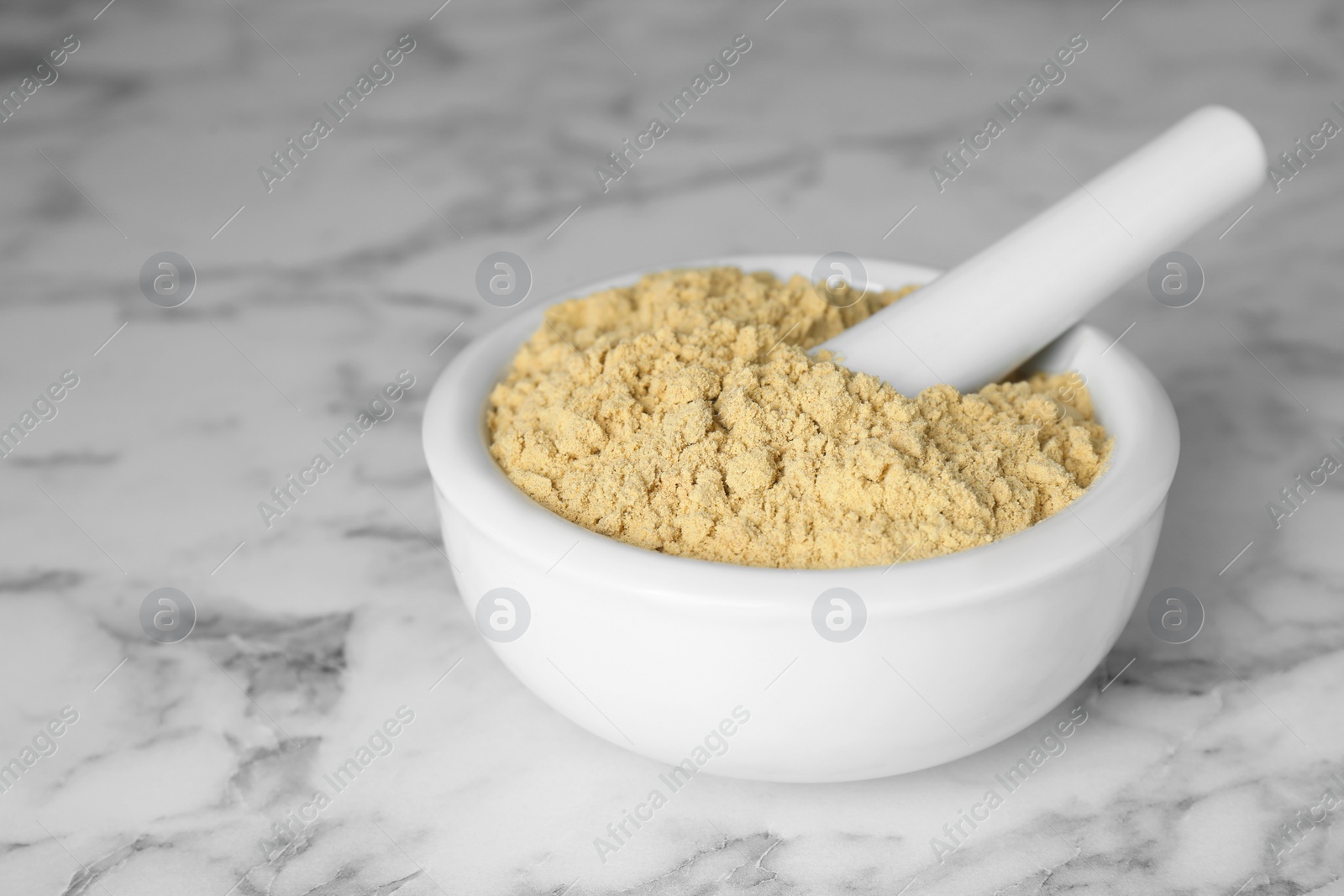 Photo of Mortar with aromatic mustard powder on white marble table