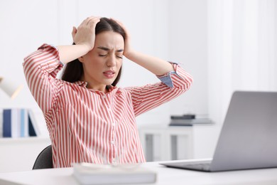 Photo of Woman suffering from headache at workplace in office