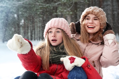 Mother and daughter having fun in forest on snow day