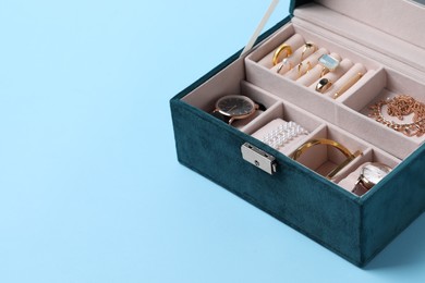 Photo of Jewelry box with many different accessories on light blue background, space for text