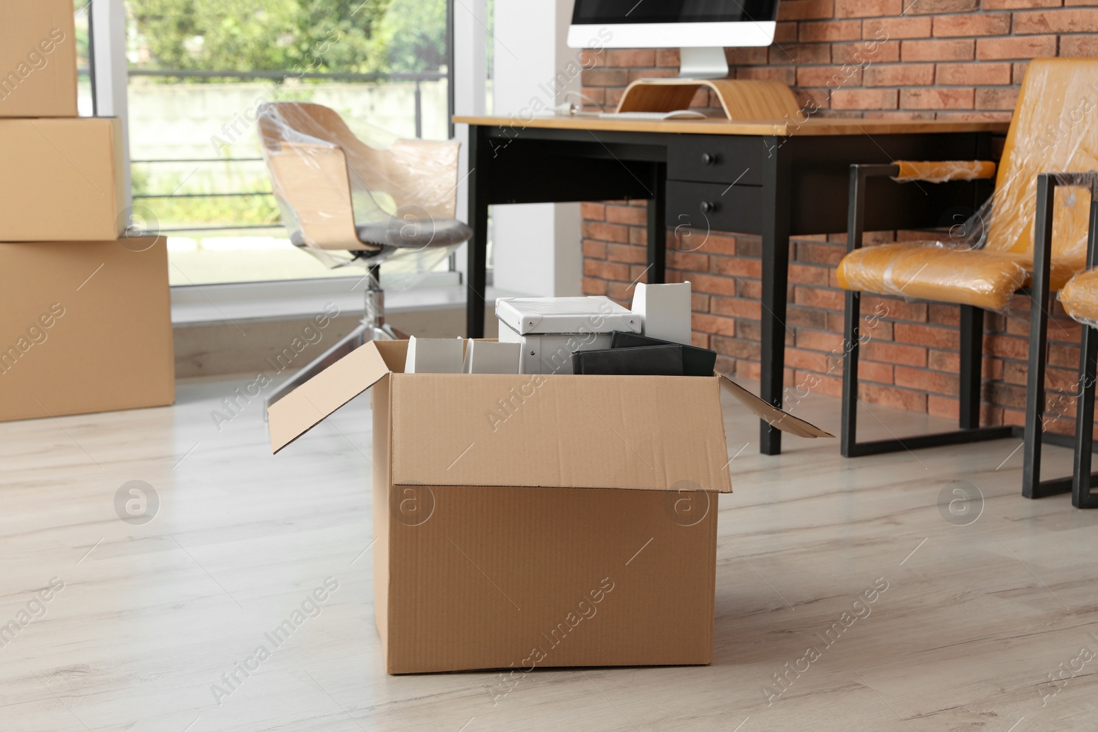 Photo of Cardboard box with belongings in office. Moving service
