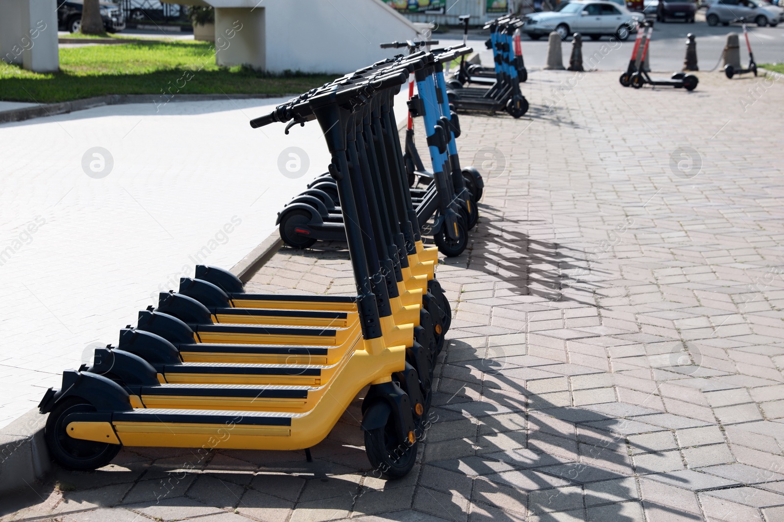 Photo of Many modern electric scooters on city street, space for text. Rental service