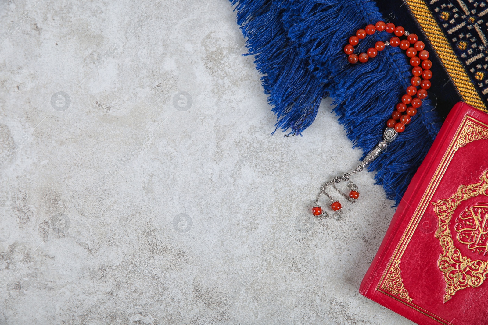 Photo of Muslim prayer beads, Quran, rug and space for text on grey background, top view