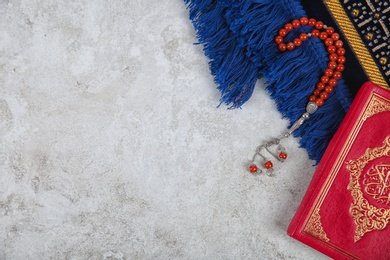 Muslim prayer beads, Quran, rug and space for text on grey background, top view