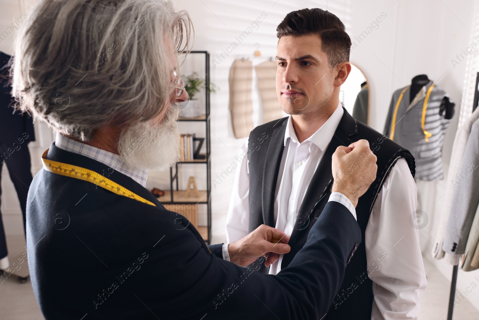 Photo of Professional tailor working with client in atelier