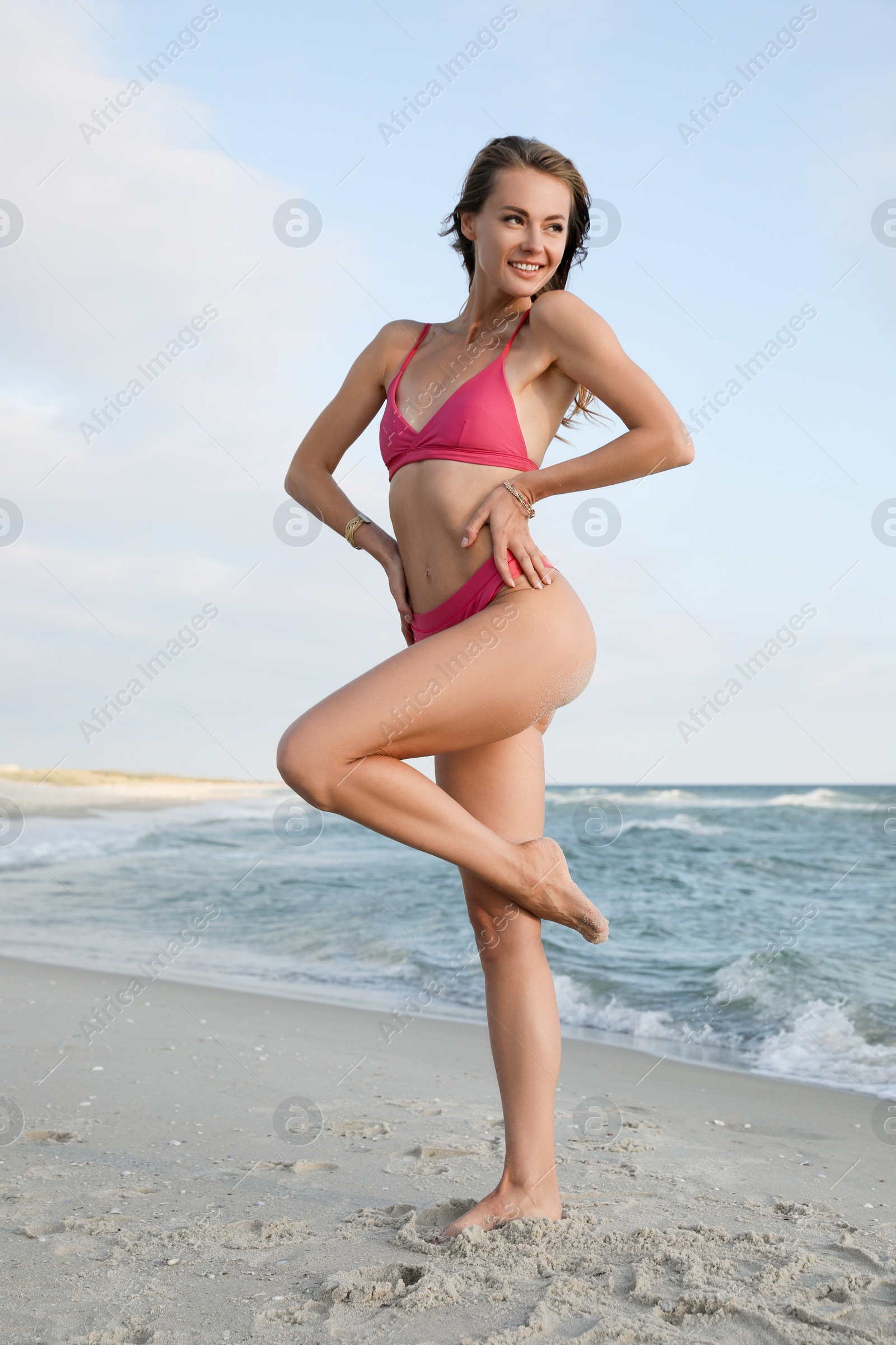 Photo of Attractive woman with beautiful body in bikini on sand near sea