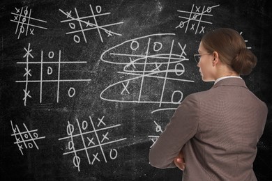Young businesswoman in elegant suit near blackboard with drawn tic tac toe game 