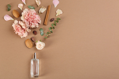 Flat lay composition with bottle of perfume on light brown background, space for text