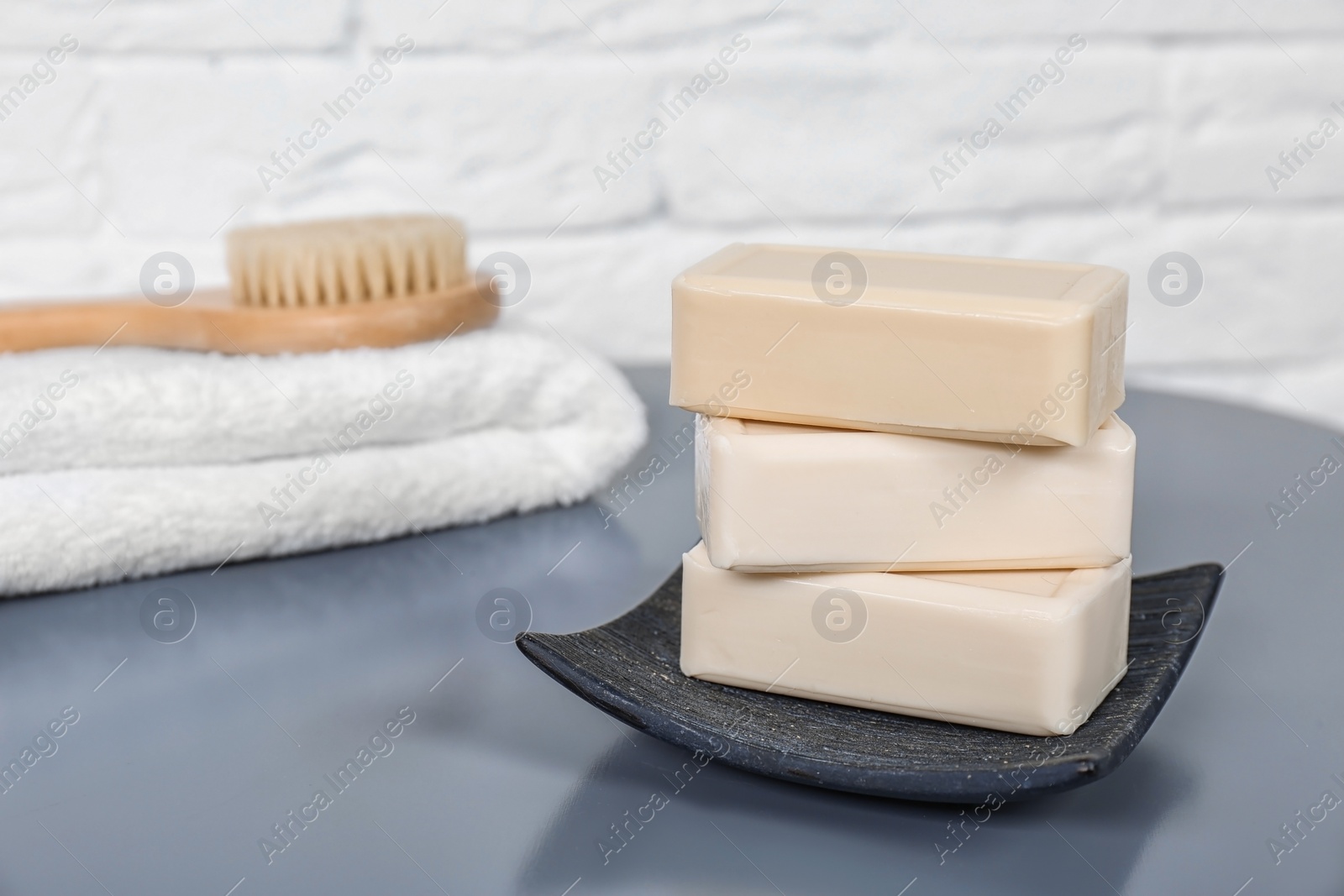 Photo of Dish with soap bars on grey table. Space for text