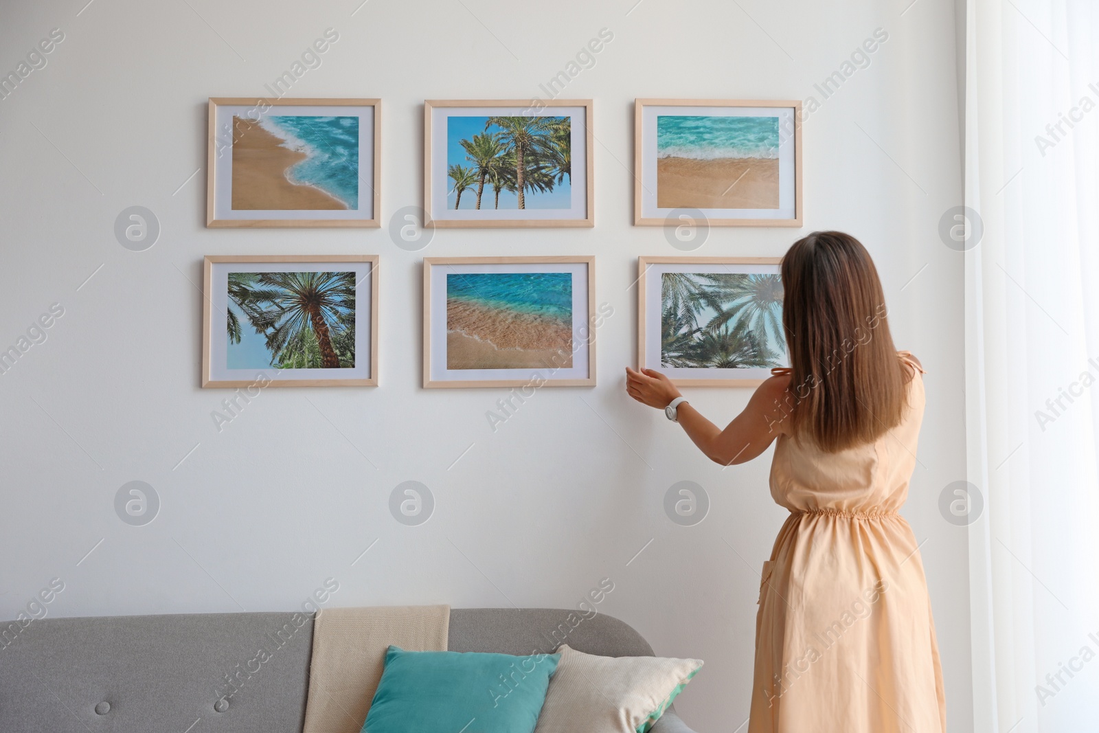 Photo of Female interior designer decorating white wall with pictures indoors