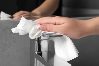 Woman cleaning faucet of bathroom sink with paper towel, closeup