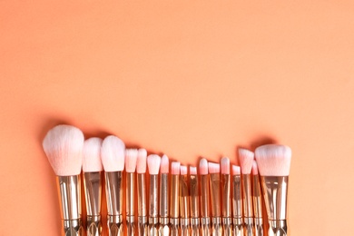 Flat lay composition with makeup brushes on orange background. Space for text
