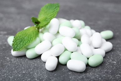 Tasty mint candies and leaves on grey background