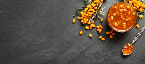 Delicious sea buckthorn jam and fresh berries on black table, flat lay. Banner design with space for text