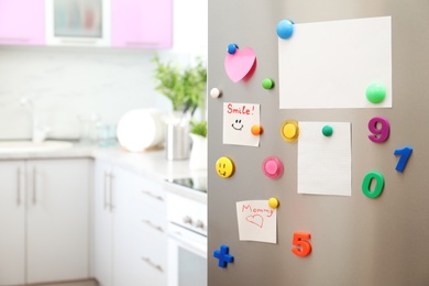 Photo of Many notes and empty sheets with magnets on refrigerator door in kitchen. Space for text