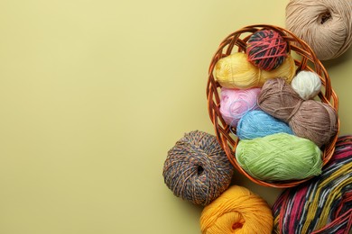 Photo of Soft woolen yarns on yellow background, flat lay. Space for text