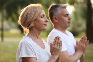 Couple practicing yoga in park at morning