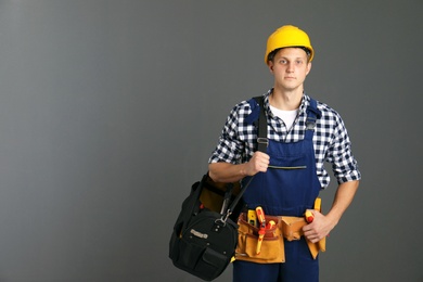 Photo of Electrician with tools wearing uniform on gray background. Space for text