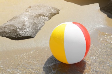 Photo of Colorful beach ball on wet sand at seaside, space for text