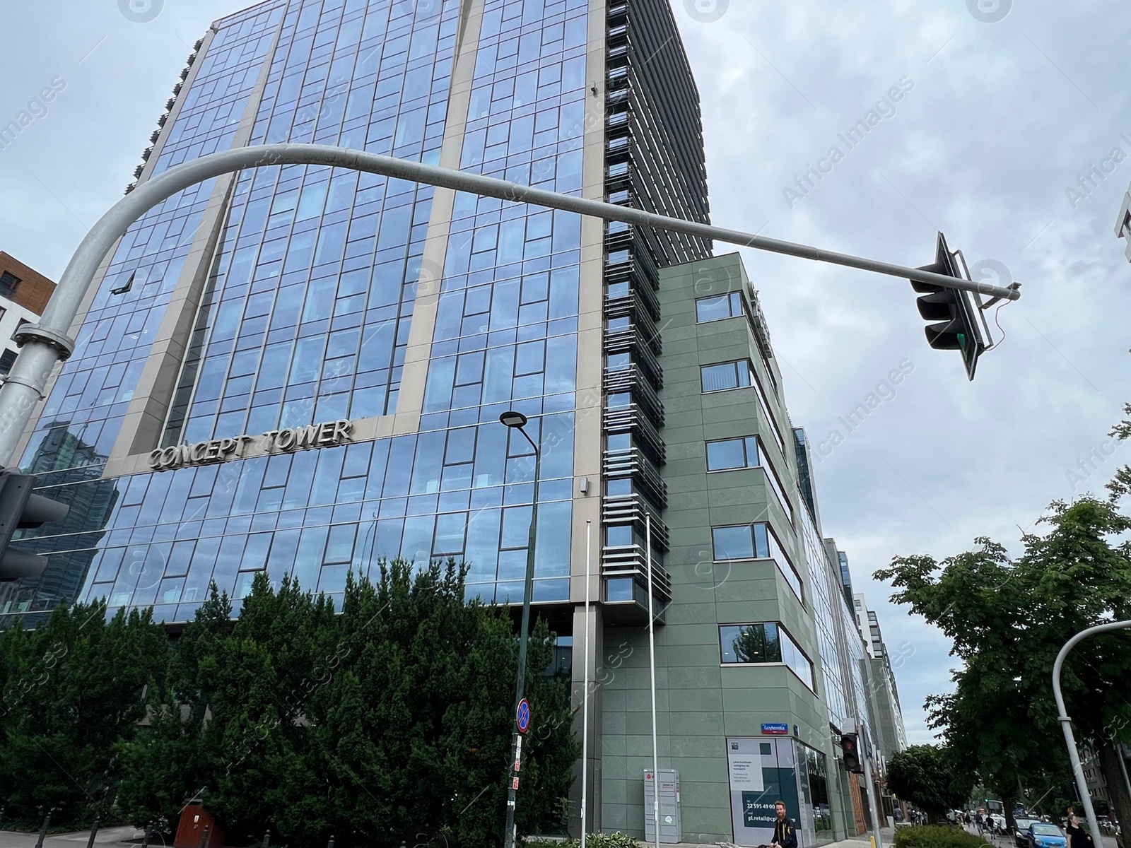 Photo of WARSAW, POLAND - JULY 13, 2022: Beautiful building and green trees against cloudy sky, low angle view