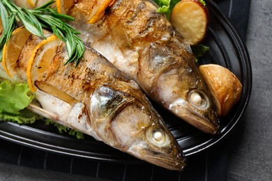 Tasty homemade roasted pike perches with garnish on grey table, closeup. River fish