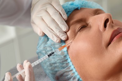 Doctor giving facial injection to senior woman in clinic, closeup. Cosmetic surgery