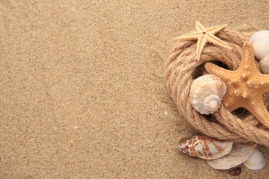 Photo of Beautiful sea stars, shells and rope on sand, flat lay. Space for text